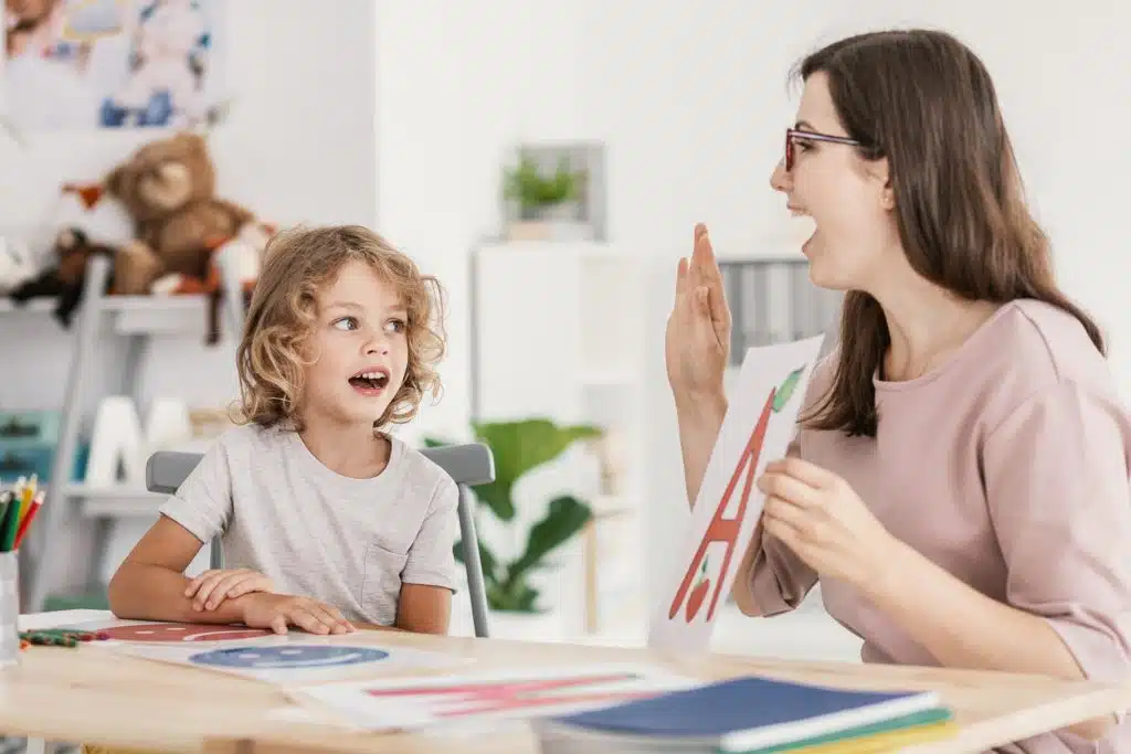 Speech therapist teaching letter pronunciation to a young boy