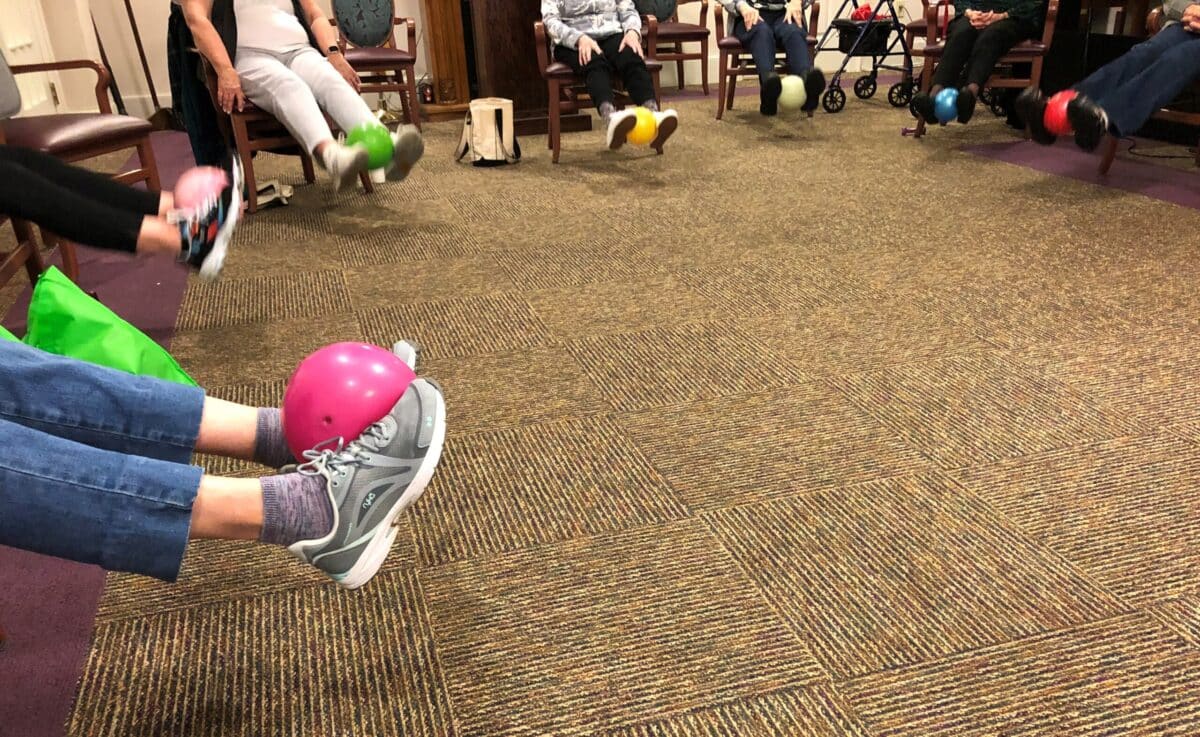 Arbors residents lift exercise balls with their feet.
