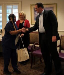 Valedictorian dressed in navy scrubs shakes hands with VP of Nursing and VHS CEO.