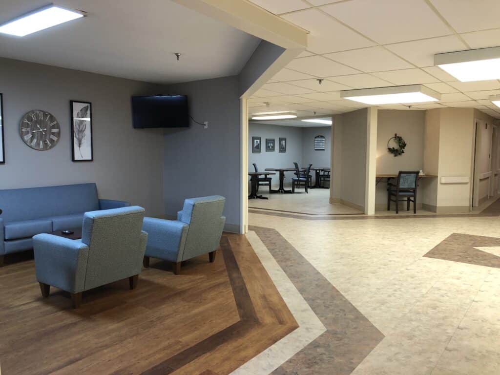 The expanded Memory Care unit at Walter Reed includes a private dining room, with spaced tables and chairs, and an open space with a couch, chairs and a television for lounging.