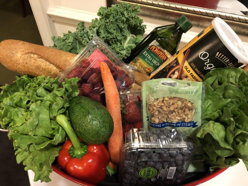 Basket of healthy foods for your mind, such as leafy greens, oats, whole grain bread, extra virgin olive oil and fresh berries.