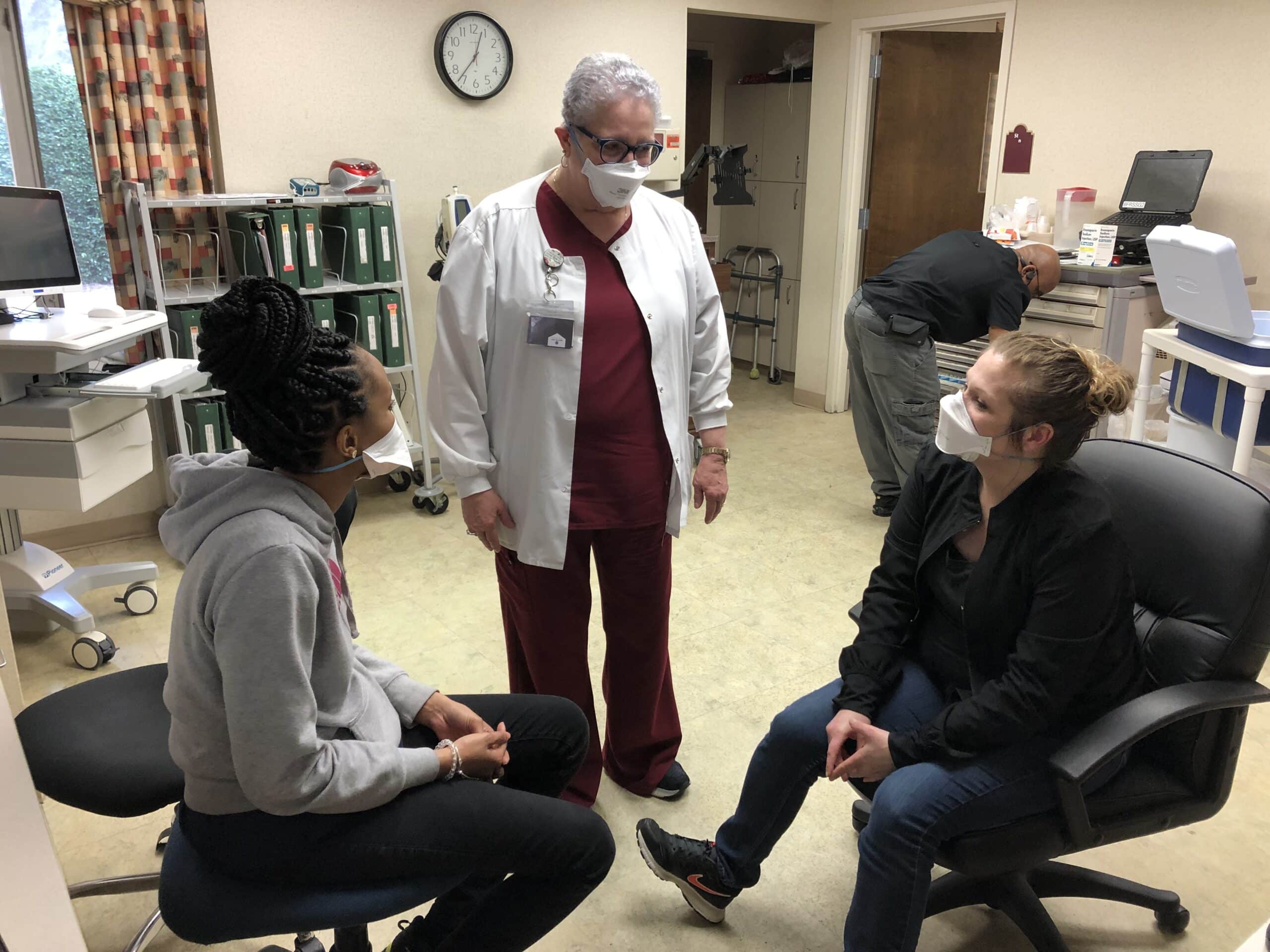 James River DON Peggy Evans speaks with two employees at the nurses station.