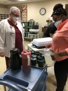 Peggy Evans looks at a woman filling glasses from a pitcher.