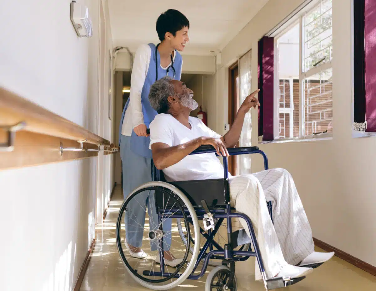 Nurse pushes elderly gentleman in wheelchair