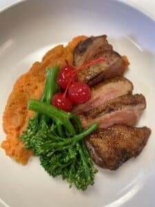 Roasted duck breast, sliced and plated with sweet mashed potatoes and broccolini. 