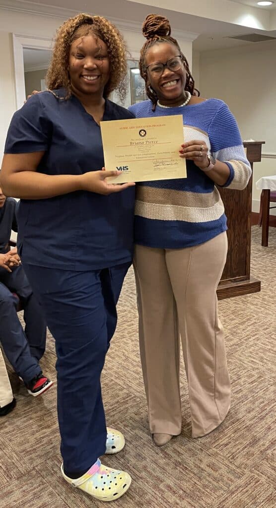 Graduate Briana Pierce holding her certificate with instructor Princess Henderson.