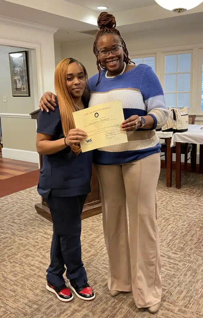 Graduate Daizhane Hunter holding her certificate with instructor Princess Henderson.