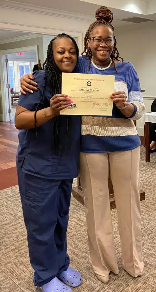 Graduate Latesha Bryant holding her certificate with instructor Princess Henderson.