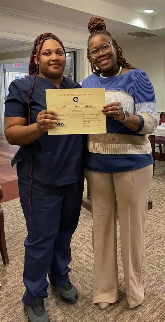 Graduate Mikayla Washington holding her certificate with instructor Princess Henderson.