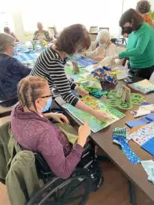 Pam and Gala work with the Residents on designing placemats in blues and greens.