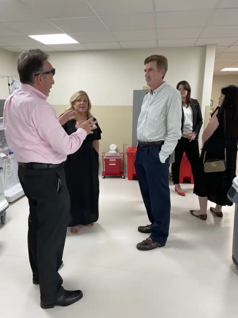 Senior VP David Crosson, left, speaks with Dr. Robert Walters and others during the open house for Coliseum's Dialysis Den